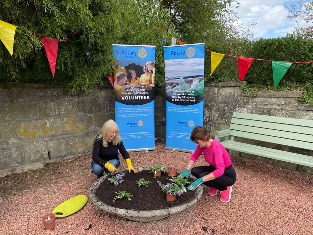 Rotary banners at a community garden event with volunteers planting