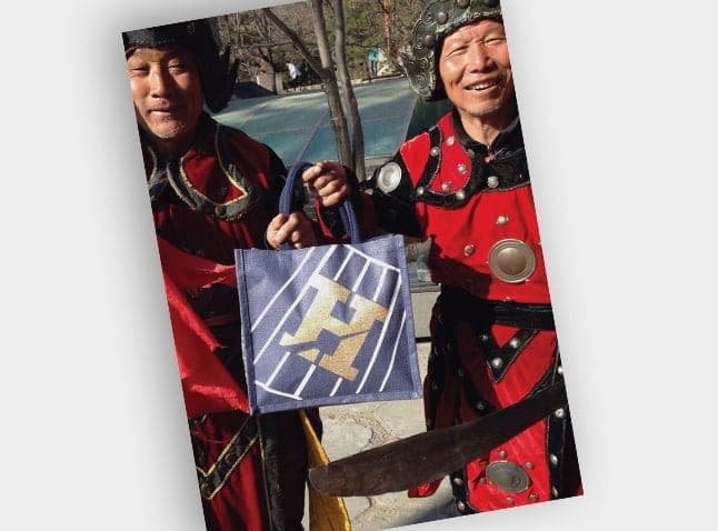 Two people in costume holding a Howieson carrier bag